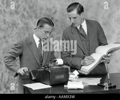 1930ER JAHRE ANGESTELLTER UND JUNGER ASSISTENT IN OFFICE MIT HAUPTBUCH & HINZUFÜGENDE MASCHINE Stockfoto