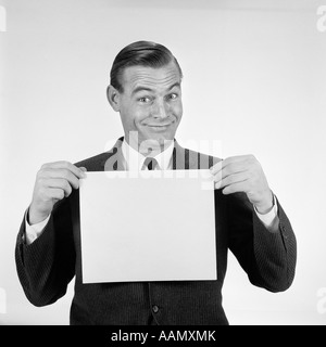 1950S 1960S LÄCHELN MANN LUSTIGE MIMIK LEER LEERE PLAKAT SCHILD HOCHHALTEN Stockfoto