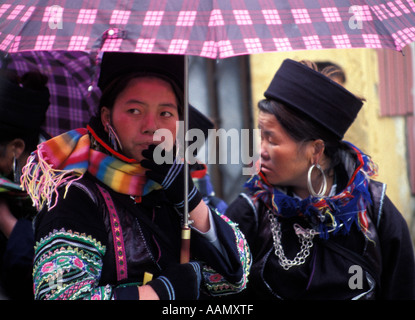 Schwarze Hmong ethnischen Minderheit Frauen Abschirmung sich mit Regenschirm, Sapa, Tonkinese Alpen, Nordvietnam Stockfoto