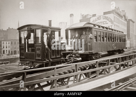 1880ER JAHRE LOKOMOTIVE & EIN PASSAGIER AUTO LÄUFT AUF EAST 42ND STREET GRUPPE VON MÄNNERN AN BORD GRAND UNION HOTEL IM HINTERGRUND Stockfoto
