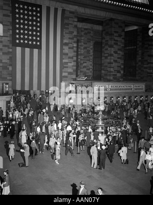 1940ER JAHREN DRÄNGEN SICH GRAND CENTRAL STATION GROßE AMERIKANISCHE FLAGGE HÄNGT AN DER WAND TICKET WINDOWS INFORMATIONEN STAND PENDLER REISEN Stockfoto