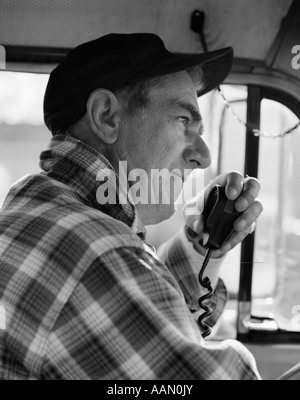 1970ER JAHREN SEITENANSICHT TRUCKER IN KARIERTES FLANELLHEMD & BASEBALL CAP MIT CB RADIO Stockfoto