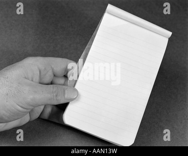 DES MANNES HAND, DIE KLEINE NOTE PAD TABLET AUSGEKLEIDET REGIERT PAPIERABDECKUNG RÜCKSEITE ZEIGT EINER LEEREN SEITE LEER NICHTS GESPIEGELT Stockfoto