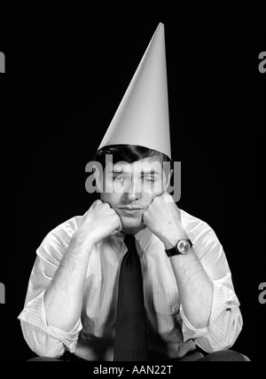 1960ER JAHRE BUSINESS MANN IM HEMD KRAWATTE TRAGEN KEGEL CHARAKTER DUNCE CAP Stockfoto
