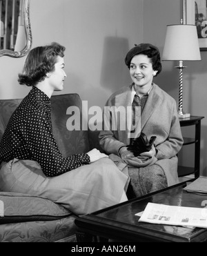 1940ER JAHREN ZWEI FRAUEN SITZEN AUF DER COUCH IM WOHNZIMMER REDEN Stockfoto