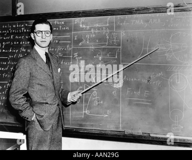 1930S 1940S MANN LEHRER PROFESSOR ZEIGT ZEIGER AN DER TAFEL, BLICK IN DIE KAMERA Stockfoto