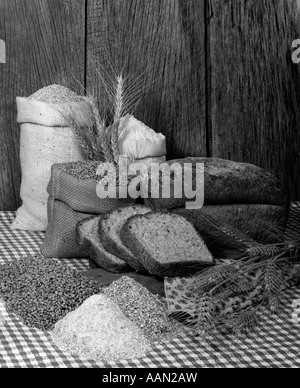 1970ER JAHREN ERNTE BAUERNHOF STILLLEBEN MIT TASCHEN VON KORN WEIZEN MEHL ROGGEN BROT & SCHEIBEN SELBSTGEBACKENES BROT Stockfoto