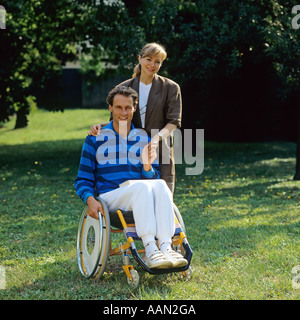 Behinderte Menschen im Rollstuhl und Frau im Garten Stockfoto