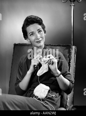 1950ER JAHREN FRAU HÄKELN BABY SOCKE BLICK IN DIE KAMERA Stockfoto