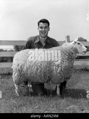 1950er Jahre Mann TEEN mit Preis HAUSSCHAF Ovis Aries suchen Kamera lächelt Stockfoto