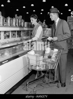 1950ER JAHREN PAAR IM SUPERMARKT IN DER TIEFKÜHLTRUHE MIT WARENKORB Stockfoto