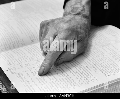 1940ER JAHRE HAND DES ÄLTEREN MANNES LESEN BIBEL ZEIGEFINGER NACH GANG ENTLANG Stockfoto