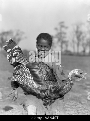 1920S 1930S AFROAMERIKANISCHEN JUNGEN LÄCHELND HALTEN GROßE TÜRKEI Stockfoto