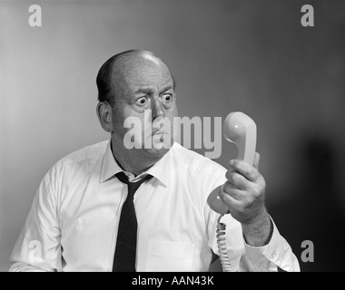 1960ER JAHREN GLATZE MANN WÜTEND IN TELEFONHÖRER Stockfoto