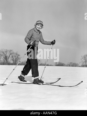 1940ER JAHREN DER 1950ER JAHRE FRAU LÄCHELND BLICK IN DIE KAMERA MIT BAMBUS HOLZ MIT SKIERN SKI POLE IN JEDER HAND TRAGEN STEPPJACKE Stockfoto