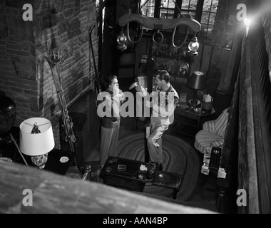 1950ER JAHREN PAAR MANN FRAU TRAGEN STRICKJACKEN REDEN IN SKI LODGE VON KAMIN BLICK VON OBEN Stockfoto