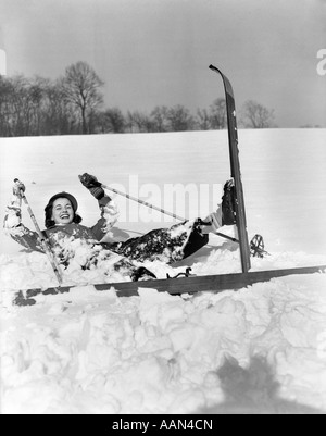 1930ER JAHREN LÄCHELNDE FRAU SKIFAHRER IN SCHNEE GEFALLEN Stockfoto