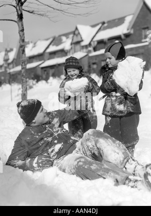 1930S 1940S SCHNEE MANN VATER ZWEI KINDER SPIELEN IM WINTER Stockfoto