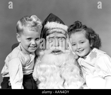 1940ER JAHRE MANN SANTA CLAUS MIT JUNGEN JUNGEN UND MÄDCHEN IN RUNDE LÄCHELN ALLE EINEN BLICK AUF KAMERA POSIEREN Stockfoto