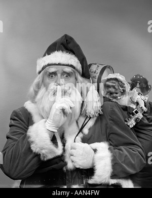 1950ER JAHREN WEIHNACHTSMANN MIT EINER TASCHE VON SPIELZEUG MACHEN GESTE BLICK IN DIE KAMERA STILL Stockfoto