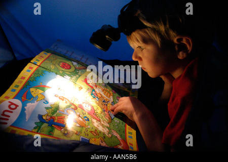 Vier Jahre alter Junge liest Comic im Zelt in den Urlaub Stockfoto