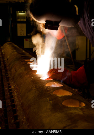 Schweißer, Schweißen von schweren Maschinen in der Kesselanlage eines Schiffes Stockfoto