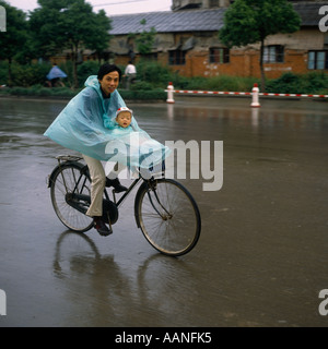 Vater und Sohn auf dem Fahrrad Radfahren auf Hauptstraße im Regen tragen wasserdicht Poncho Cape in der Provinz Jiangsu Suzhou China Stockfoto