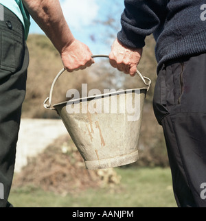 Ältere Frau und Mann im Garten halten Blecheimer Stockfoto