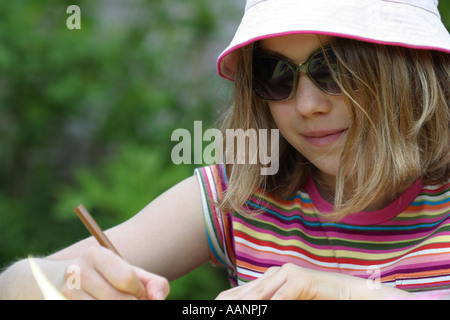 Junges Mädchen im Alter von 12 Jahren Kunst Arbeit im Sommer Garten tragen rosa Hut und Sonnenbrille Stockfoto