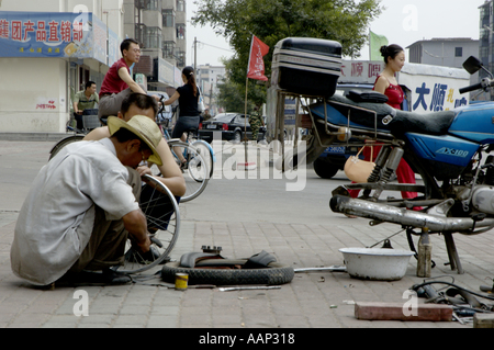 Männer, die Reparatur des Schlauch-Reifens ein Motorrad auf dem Bürgersteig, Datong, Shanxi, China. Stockfoto