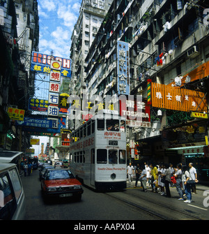 Belebten engen Straßenszene in Wanchai District Menschen warten auf Straßenbahn rot taxi auf linken Seite viele chinesische Zeichen overhead in Hong Kong Stockfoto