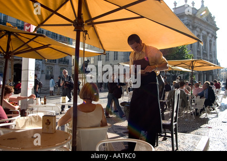 Ein großer Kellner nimmt eine Bestellung von einer jungen Frau in einem Straßencafé in Lissabon Portugal Stockfoto