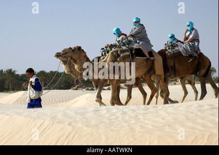 vier britische Touristen auf Kamelen, geführt von Beduinen führen durch Sanddünen in der Wüste Sahara Douz Tunesien Stockfoto