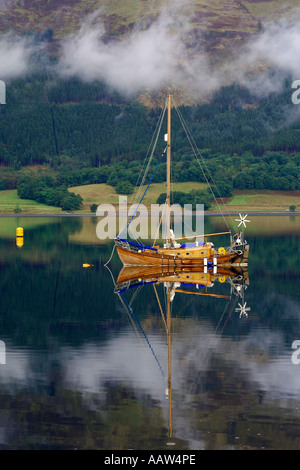 Sehr schön traditionell gebaut aus Holz Segelboot vor Anker am Loch Leven in der Nähe von Ballachulish Glencoe mit leichten Wolken treiben durch Stockfoto
