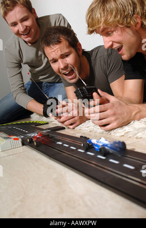 3 junge Männer mit Carrera-Modell-Eisenbahn Stockfoto