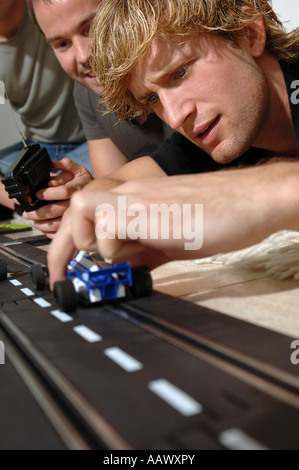 3 junge Männer mit Carrera-Modell-Eisenbahn Stockfoto