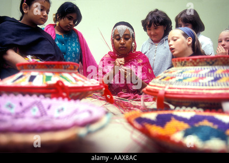 Eine Demonstration der traditionellen Korbflechten durch eine asiatische Frau in einer Grundschule in London. Stockfoto