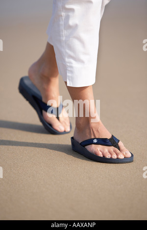 Weiblich 20 s 30 s Füße zu Fuß am Sandstrand tragen Flip Flops Stockfoto