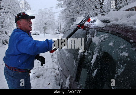 Mann, kratzen aus Schnee und Eis von einem Auto Automobil nach einem Schneesturm Stockfoto