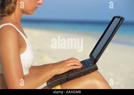 Frau am Strand mit Laptop während Arbeitsurlaub Stockfoto