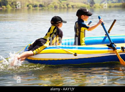 zwei jungen 6 tragen Anzüge spielt in einem Schlauchboot auf See Stockfoto