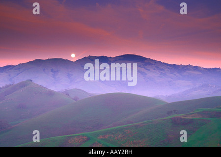 Vollmond über Bergen über nebligen neblig Bergkette bei Sonnenuntergang horizontale Stockfoto