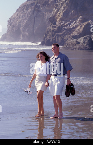 paar Leute in der Liebe zu Fuß entlang des Strandes, die Hand in Hand und barfuß Stockfoto