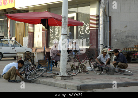 China Shanxi Datong reife Männer reparieren ihre Fahrräder auf dem Bürgersteig Stockfoto