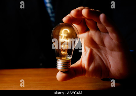 Mann, hält die Glühbirne mit Pfund-Zeichen als filament Stockfoto