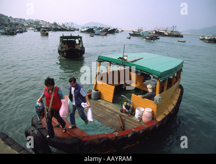 Ein Mann und eine Frau steigen aus einer kleinen Fähre im Hafen von Cheung Chau, Hongkong, China Stockfoto