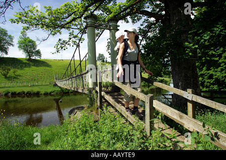 Eine Frau und ein Baby in einem Rucksack-Träger überqueren eine Brücke während des Gehens der Yorkshire Dales Weg, England, UK Stockfoto