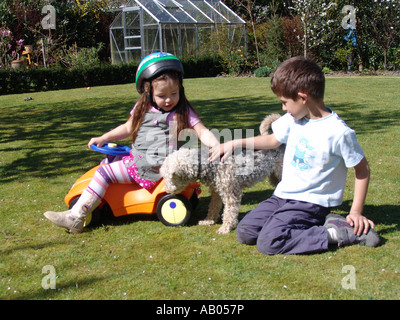 Zwei Kinder spielen im Garten mit ihrem Welsh Terrier Hund in Almere, Holland Stockfoto