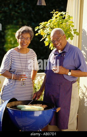 Afrikanische amerikanische Ehepaar im Ruhestand, grillen Fleisch und Maiskolben auf ihrer Veranda Stockfoto