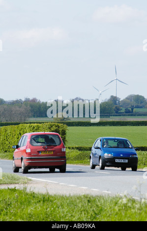 Verkehr auf der belebten A47 in Swaffham Norfolk vor dem Hintergrund der landwirtschaftlichen Landschaft und Windturbinen. Stockfoto